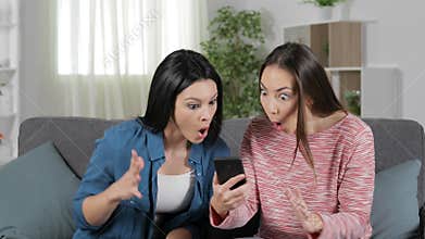 Two surprised friends finding phone content