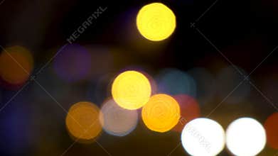 Defocused or soft focus bokeh lights of cars, scooters, motorbikes and traffic driving on city streets at night