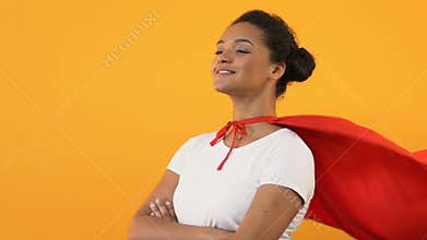 Self-confident afro-american woman with crossed hands in red cape, super hero