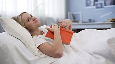 Dreamy book lover inspired by interesting bestseller, lying in bed, imagination