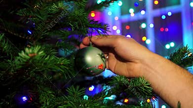 Hand man decorating on Christmas tree with Christmas glow lights.
