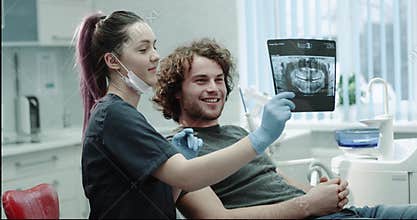 Happy patient at dentist have a friendly conversation with his doctor , the dentist shows to the patient his results of