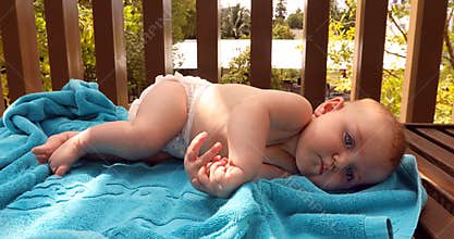 Funny baby lying on towel in cot