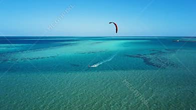 Aerial view young man kite surfing in tropical blue ocean