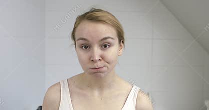 Woman using mouthwash in bathroom.