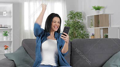 Euphoric woman checking phone celebrating success