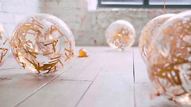 Like cat slowly and carefully sneaking up to its goal, transparent balloons lie on light wooden floor, golden shiny