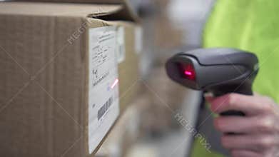 Hand holds a barcode scanner in the warehouse