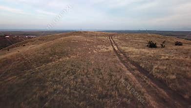 Flying over country road through dry land and hills