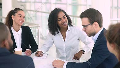 Diverse businesswoman and businessman make deal handshaking at group meeting