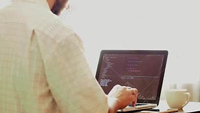 Young programmer coding on a laptop in office