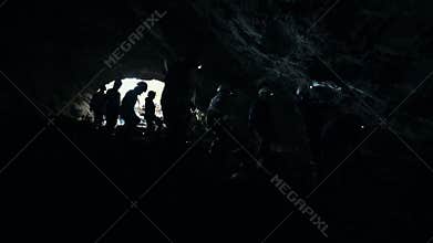 A wet rocky cave. People explore a dark cave with light equipment