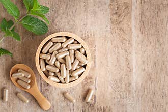 Herbal capsules in cup on wooden table background . Top view of medicine for healthy and capsules the spoon wooden