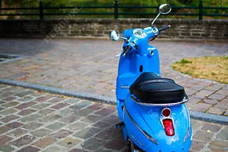 Blue classic scooter or vespa Peugeot Django parked in the street