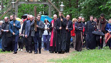 Group of catholic people and priests carry cross through cavalry way in forest