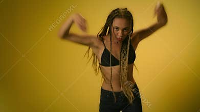 Flexible woman showing modern dance elements in studio on yellow background