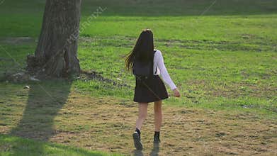 Brunette walks on grassy meadow in slow mo. Model has nice legs and short skirt.