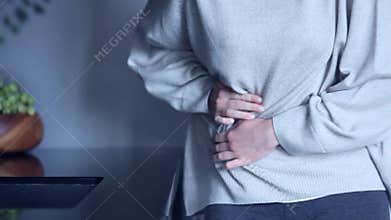 Woman has stomach ache in kitchen