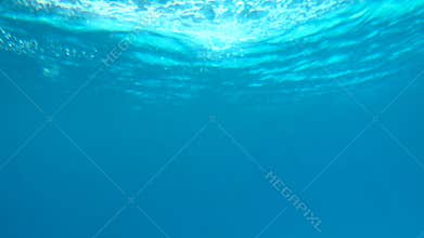 Beautiful under water video of dark blue sea water and sun ray shining through surface
