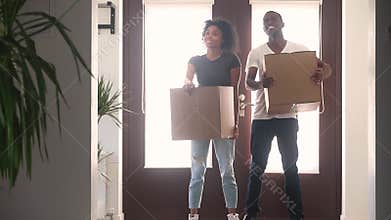 Happy black couple holding boxes talking embracing standing in hallway