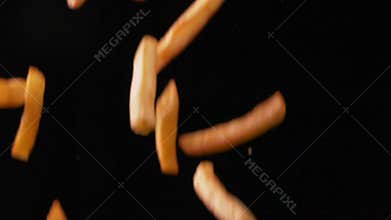 Delicious french fries falling on black background