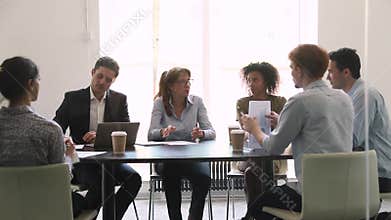 Serious mature female business leader talking at diverse group negotiation