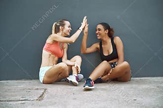Laughing friends high fiving during a break from their workout