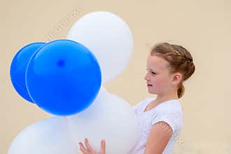 Happy little girl with blue and white balloons.