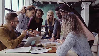 Top view of young team working on architectural project. Group of mixed race people standing near table and discussing.