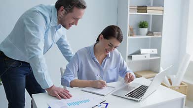 Young office worker helping female colleague with project