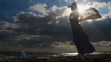 Timelapse of strong woman alone on seashore, female silhouette, dark cloudy sky