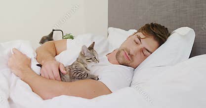Young man sleeping on bed holding cat in his arms 4K 4k