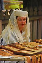Romanian woman in traditional costume selling handicraft at local flea market