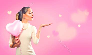 Valentine`s day. Beauty girl with pink heart shaped air balloon pointing hand