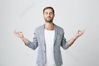 Yoga and meditation. Handsome man with beard dressed in jacket keeping eyes closed while meditating, feeling relaxed