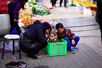 Young baby in the box with his mum and his brother - Street market in Kunming