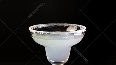 Process of serving margarita cocktail. Bartender pouring alcohol drink into a glass close-up.