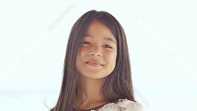 A charming filipino schoolgirl joyfully poses, rotating her hair. Face close-up on a white background of summer nature.