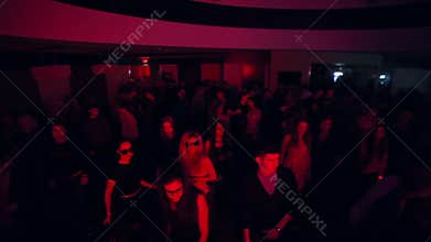 Men and women dance to sounds of music in night club. Jib shot