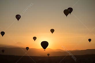 Hot air balloons in the sky during sunrise. Flying over the valley at Cappadocia, Anatolia, Turkey. Volcanic mountains in Goreme n