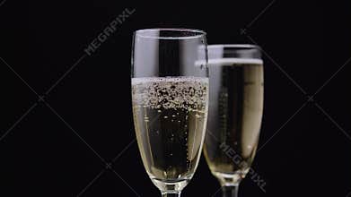 Champagne poured into glass. Black background. Close up