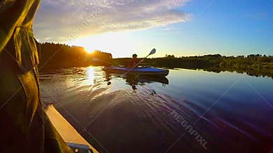 Silhouettes of two males kayaking at sunset, active rest, slowmo