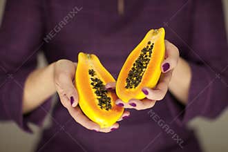 Woman in violett 50`s dress hands holding some papayas