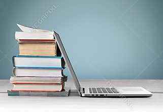Stack of books with laptop on table