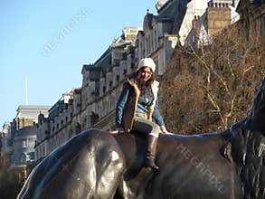 Fashionable Young Woman Poses Atop Bronze Lion, London, England, UK