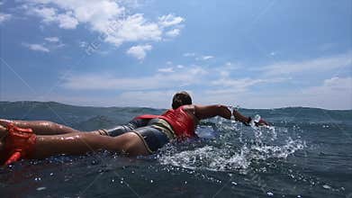 Surfer paddles in the ocean
