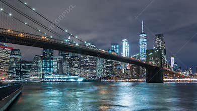 Manhattan skyline and Brooklyn bridge at night. Timelapse. Tall buildings on background, New York, NYC