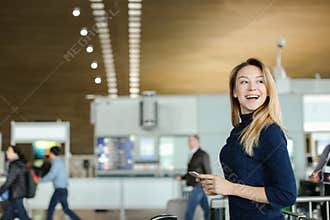 Caucasian pretty woman chatting by smarphone at airport hall.