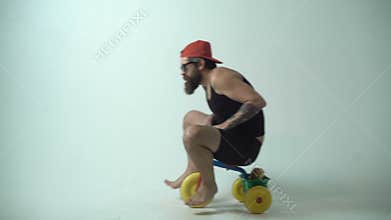 Delivery service. Not baby delivery. A funny bearded man is riding a children`s bicycle.