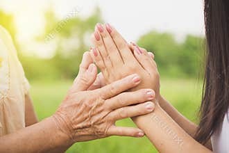 Asian daughter greeting or pay respect to her mother, two hands holding each others